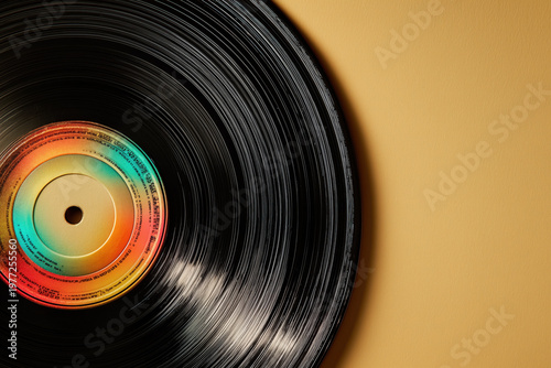 Vinyl record with rainbow grooves on warm beige background close-up
