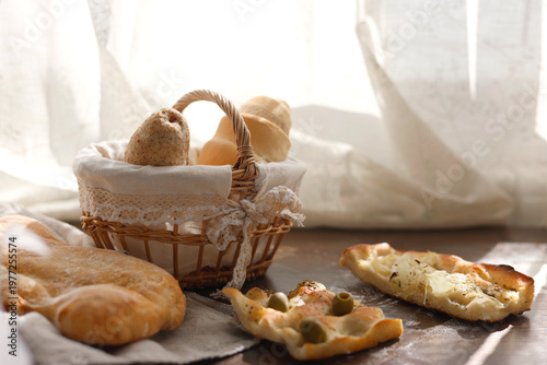 Bild auf Leinwand Assorted Italian focaccia and fresh bread rolls in wicker basket on table