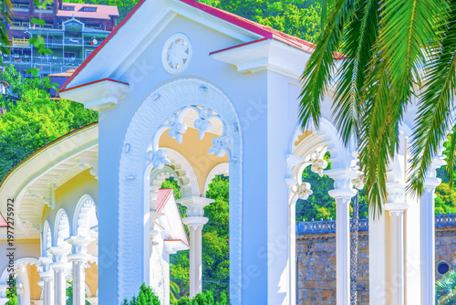 Famous white Gagra Colonnade with decorative arches and palm trees in Abkhazia.Ideal background for travel, summer holidays, tourism concepts.Summer vacation vibes at the Black Sea coast resort.