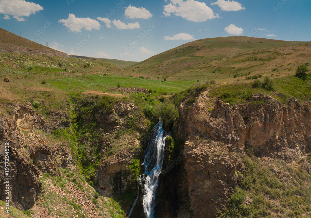 Obraz premium A view of a waterfall cascading down from the rocks. Nature and spring as the backdrop.