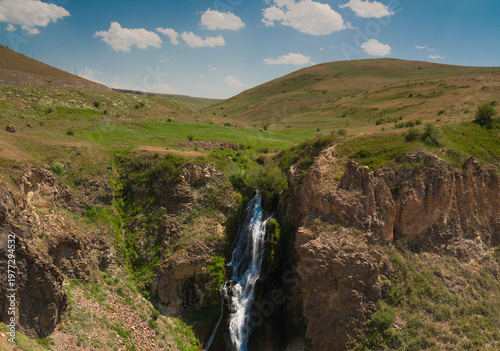 A view of a waterfall cascading down from the rocks. Nature and spring as the backdrop.