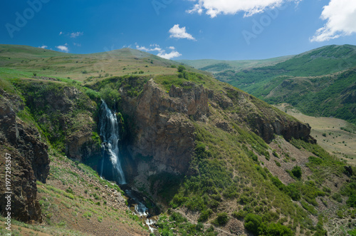 A view of a waterfall cascading down from the rocks. Nature and spring as the backdrop.