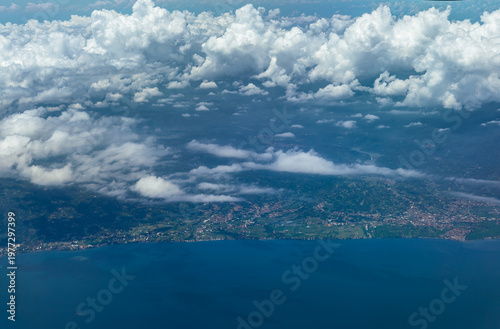 Aerial view of Bali coastline with villages, farmland and shoreline under scattered clouds.