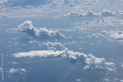 Fotografie Isolated cloud formations over ocean with visible light rays seen from airplane at high altitude