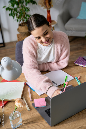 Foto Teen girl happily using her laptop in a cozy apartment, embracing creativity