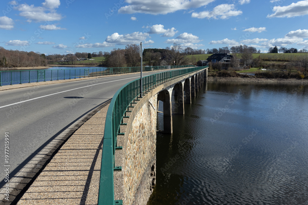 Fototapeta premium View of Pont d'Haelen bridge, and Robertville Lake, at Robertville-les-Bains, Waimes, Belgium, on a beautiful sunny spring day. Road trip through the Belgian Ardennes.