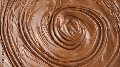 Macro texture of glossy chocolate nut cream swirling patterns