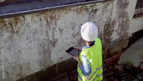Foto Engineer in hardhat and hi-vis vest documenting severe water damage, rising damp