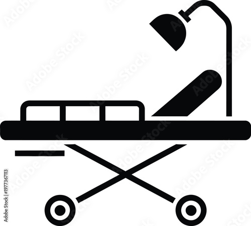 Black and white of a hospital gurney with an adjustable backrest and an overhead examination lamp mounted on a wheeled frame for patient transport in a clinical medical facility setting