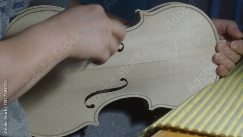 Fotografie Close Up Of A Violin Maker Carefully Carving The F Holes And Edges Of A New Unfi