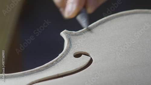 Artisanal Craftsmanship A Luthier Meticulously Carves the Delicate Purfling Inlay Along the Soundhole Edge of a Violin Body Revealing the Skilled Hands of a Master Instrument Maker at Work