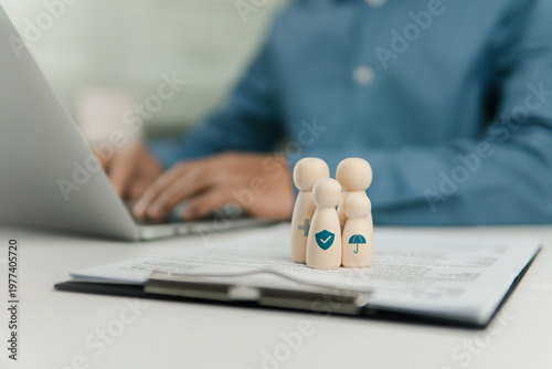 Obraz na płótnie Health insurance planning concept with wooden family toy and icons on document, businessman working on laptop for financial security, life protection, medical coverage and retirement investment