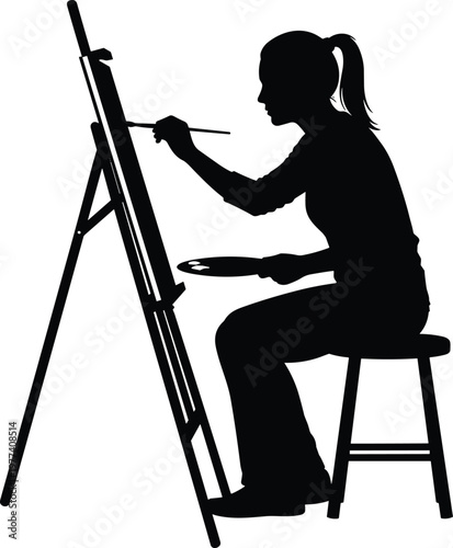 Silhouette of a talented female artist sitting on a stool and painting on a professional canvas easel using a brush and palette in a studio.