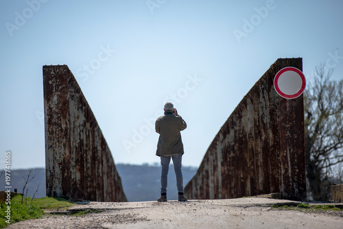 Man Standing on Rusty Bridge with Symmetrical Perspective