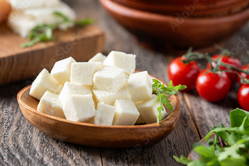 White cheese cut into cubes served on wooden heart shaped plate. Rustic