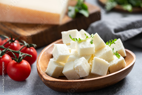 White cheese cut into cubes served on wooden heart shaped plate. Rustic