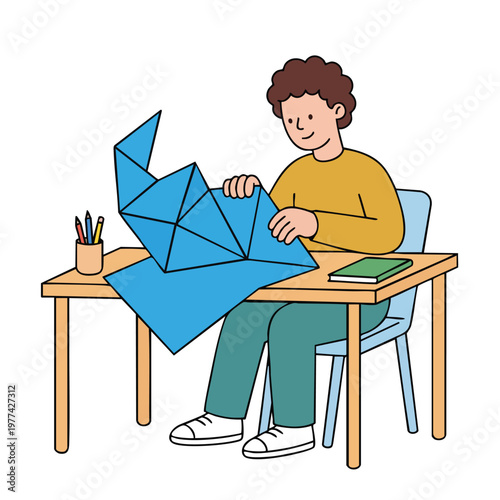 Young boy engrossed in origami art project at desk.