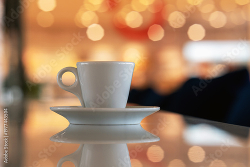 A cup of coffee and multicolored defocused bokeh lights background with copy space for text. Glimmering lights reflecting on a tabletop, beautiful blurry background, celebration and christmas concept.