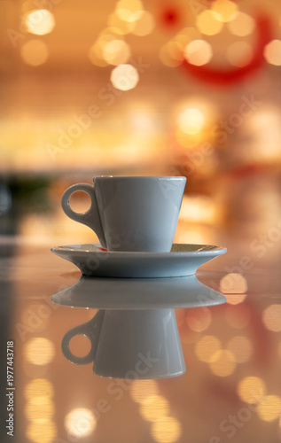 A cup of coffee and multicolored defocused bokeh lights background with copy space for text. Glimmering lights reflecting on a tabletop, beautiful blurry background, celebration and christmas concept.