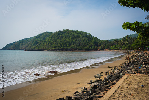 фотографія Scenic beach with gentle waves and lush green hills along the coastline in Gokar