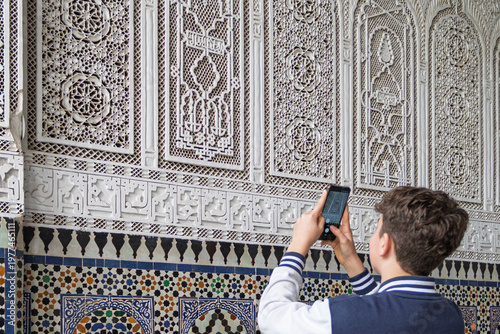 Tourist photographing moroccan intricate islamic architecture and mosaic