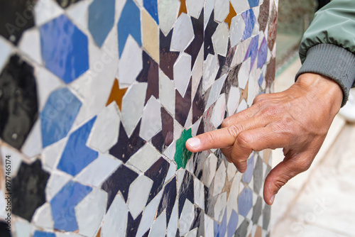 Hand pointing at traditional moroccan zellij tile pattern