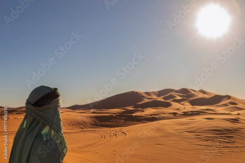 Berber man viewing sahara desert sand dunes at sunset