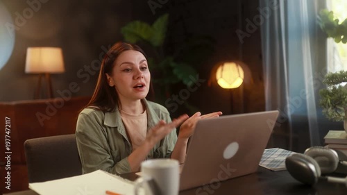 Young woman having a heated argument over a video call on her laptop at home, reacting emotionally with visible anger and frustration, engaged in a tense and stressful online conversation
