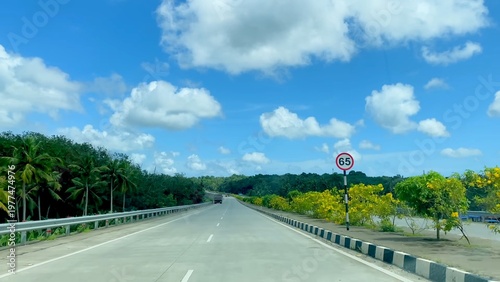 Canvastavla Scenic Kerala highway with lush greenery and road sign showing 65 kilometer dist