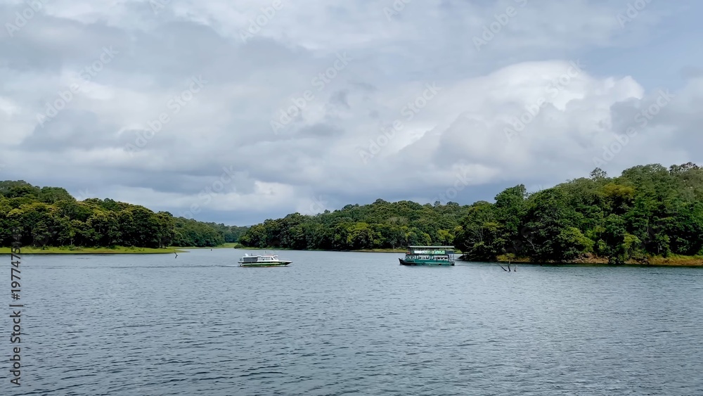 Fototapeta premium Scenic Kerala riverside with tourist boat on calm water, showcasing tropical greenery, peaceful environment, and travel destination in India