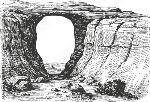 Natural stone arch carved by river flow in rugged canyon landscape with rocks and shrubs