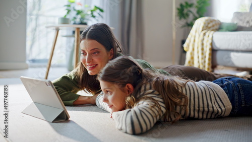 Aunt niece watching tablet lying soft carpet closeup. Mom girl enjoying online