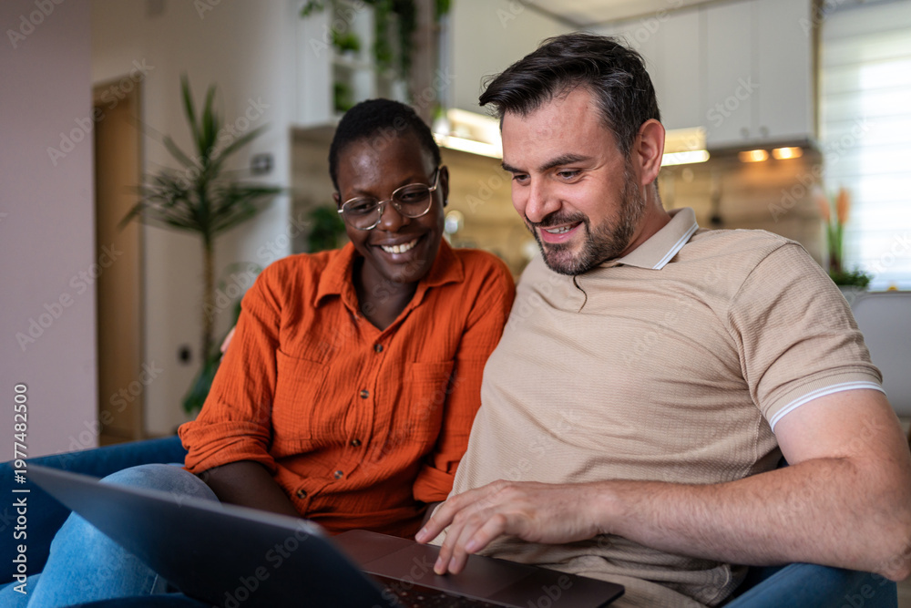 Obraz premium Couple sharing joyful moments while working on a laptop in a cozy living room setting