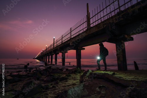 Dramatic moning sky over a rocky beach with a traveler.