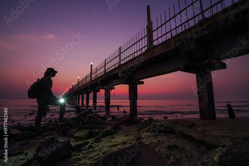 Silhouette of a person exploring a rugged coastline during sunrise.