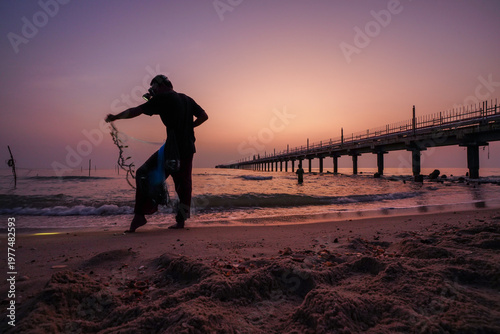 fisherman walking on the beach at sunrise