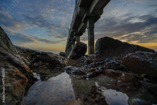 Atmospheric sunrise landscape with a bridge stretching into the sea.