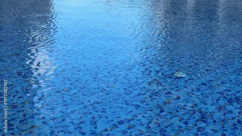 Swimming pool water surface with blue mosaic tiles in background
