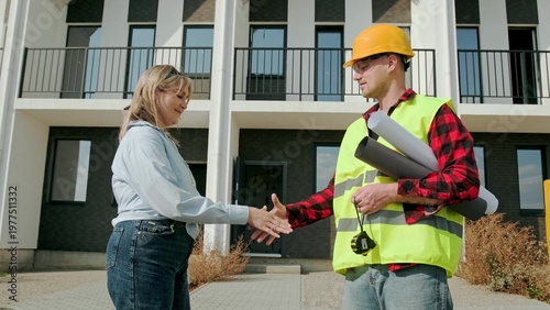 Cheerful construction specialists welcoming one another on building site