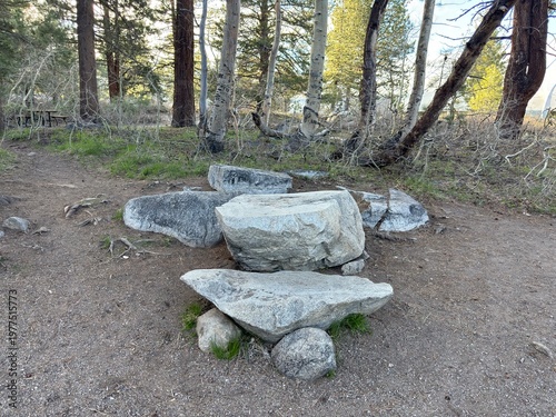 Fotografie Natural Forest Clearing with Boulder Seating: Large boulder formation on a forest floor naturally forming a seating and gathering area with a rustic stone table setup