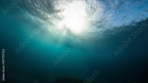 Underwater view of sunlight streaming through the ocean surface, creating light rays in the deep blue water