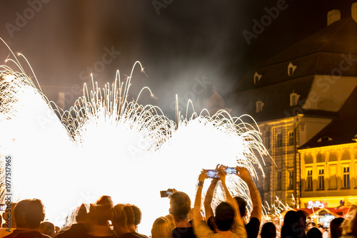 Long exposure motion blurred photograph. SIBIU, ROMANIA: People are watching a firework display in a city square