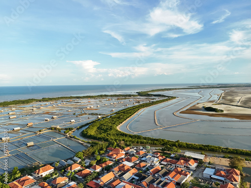 Aerial view of coastal salt ponds, winding lagoons, and seaside village with red roofs