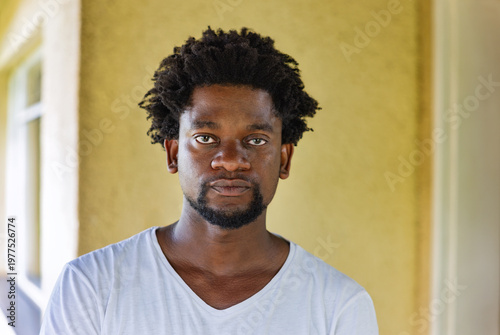 Portrait of a Smiling Young African Man with an Afro Hairstyle blurred green outdoor background.
