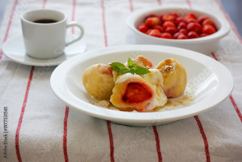 Homemade strawberry dumplings made from quark dough, served with powdered cane sugar and quark, traditional summer dessert popular in Czechia, Slovakia, Austria, Poland and Central Europe
