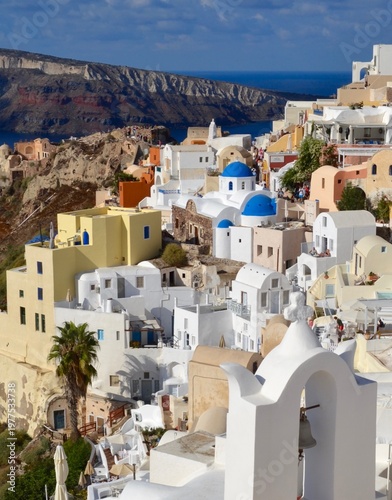 Oia, a picturesque village in Santorini, Greece,  features iconic Cycladic architecture with white-washed buildings and blue domed roofs. 