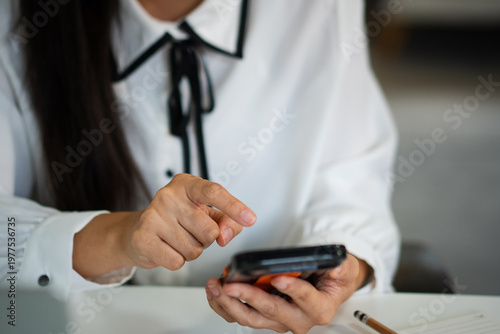 Photography Close up A businesswoman uses her mobile phone while working on a laptop at the