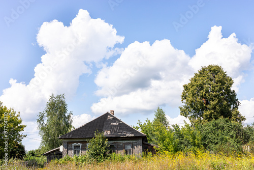 Abandoned wooden house surrounded by overgrown vegetation and trees