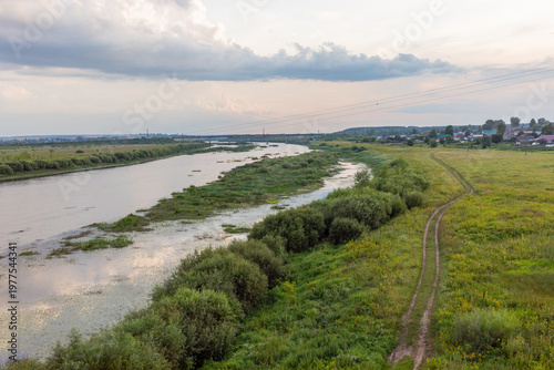 Landscape with river in summer evening with swampy river banks with overgrown vegetation