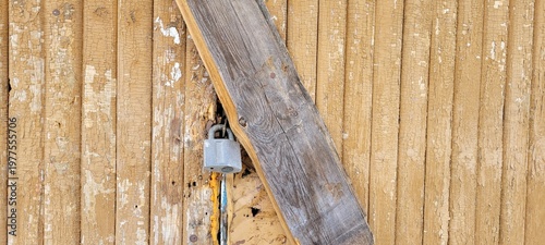 close up of a vintage weathered wooden door secured with a metal padlock